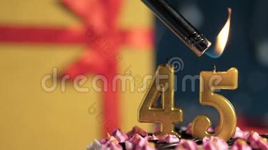 生日蛋糕45号金色蜡烛用打火机点燃，蓝色背景礼品黄色盒子用红丝带系好
